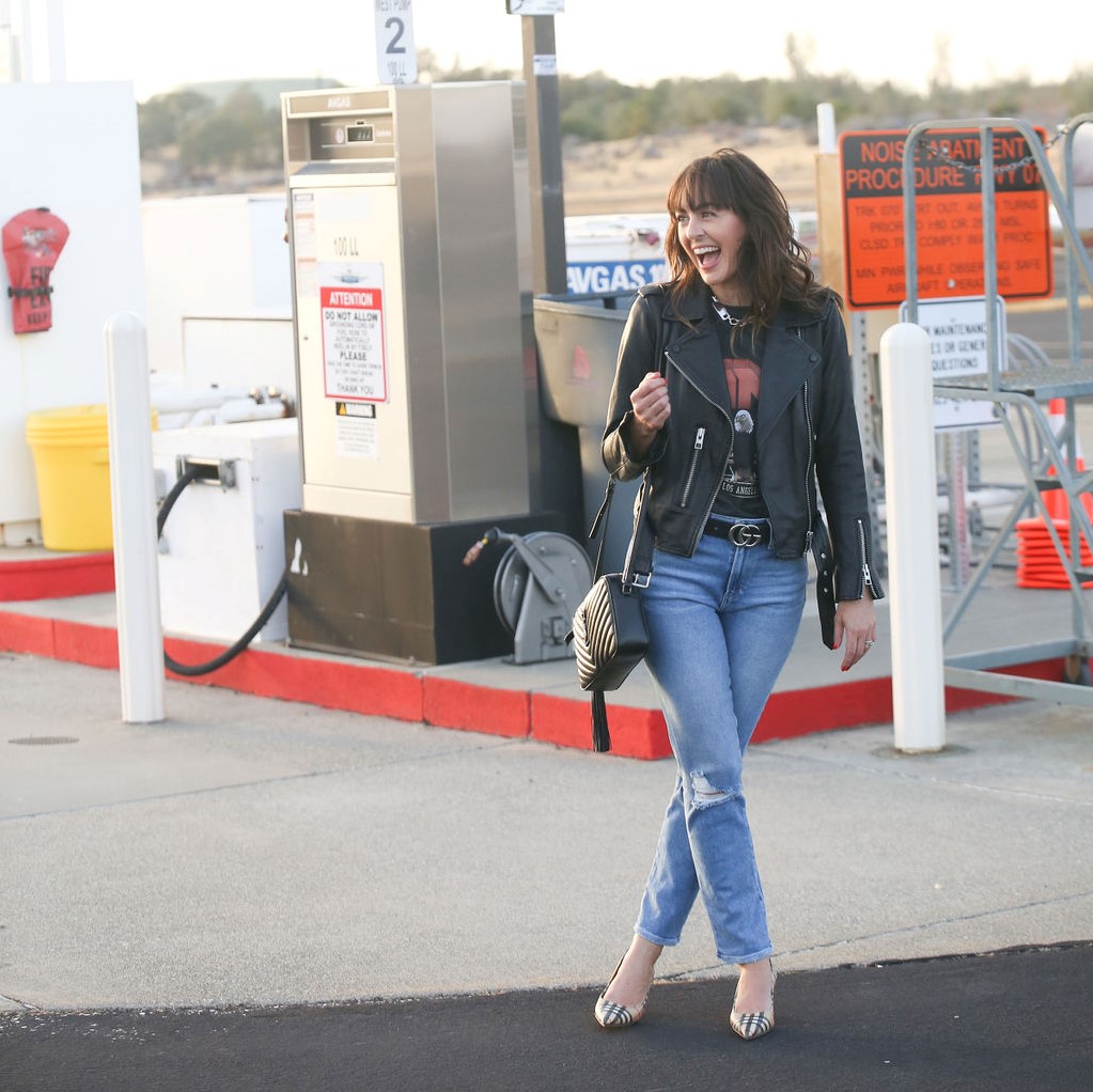 Jennifer Sattler Stylist black belt with gucci buckle graphic t-shirt anine bing t shirt with eagle silver chain necklace burberry plaid kitten heels airport photo shoot black leather all saints jacket
