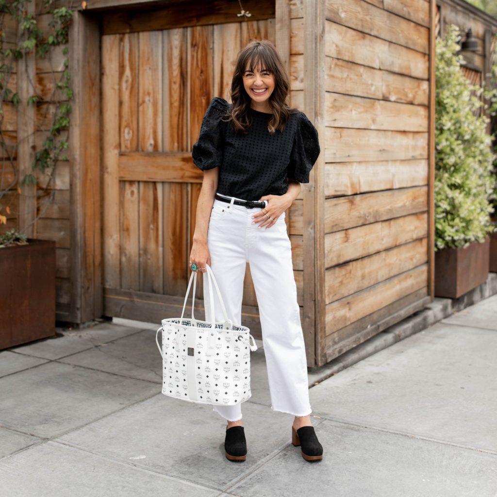 Jennifer Sattler Stylist wearing white wide leg crop jeans from Nordstrom a black puff sleeve eyelet blouse from Target #target style MCM reversible tote black clogs DSW and black on black gucci belt
