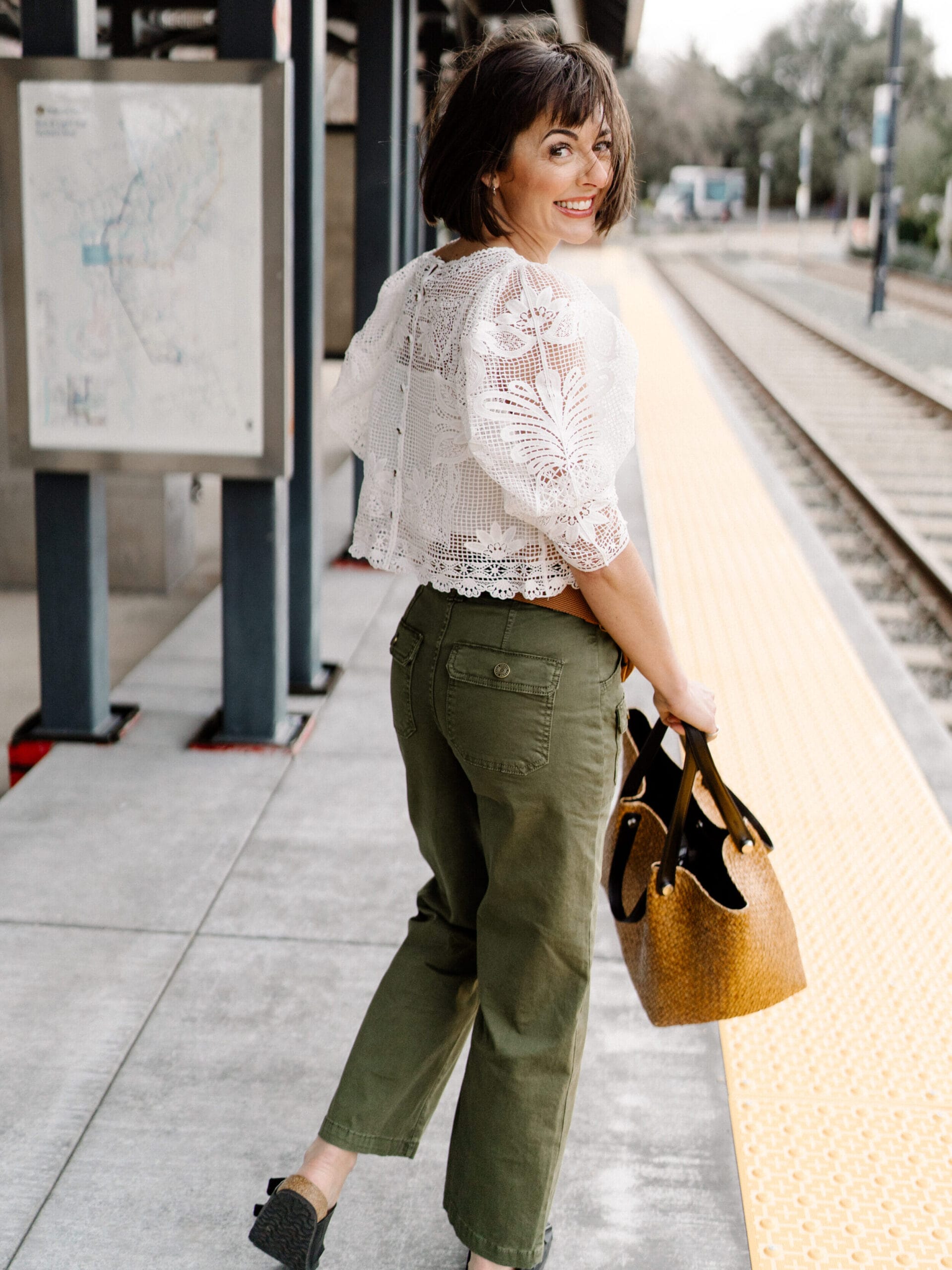 Jennifer at a train station wearing a Lace Top | Tote | Birkenstocks | FRAME Utility Pants
